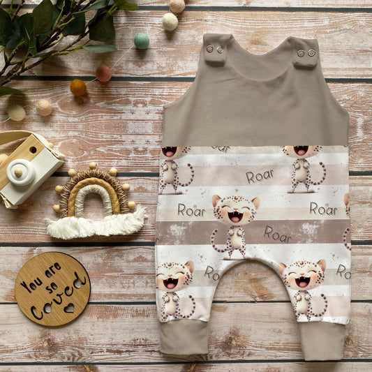 Handmade Baby Strampler „Roar Kitty“ in Beige aus weichem French Terry, mitwachsend, mit Leo-Babykatzen Druck und Knöpfen an den Schultern, dekoriert mit Holzspielzeug und Makramee-Regenbogen